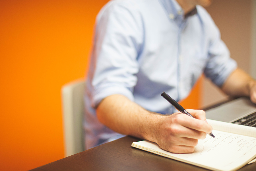 Select Data: Man writing with pen and paper at desk